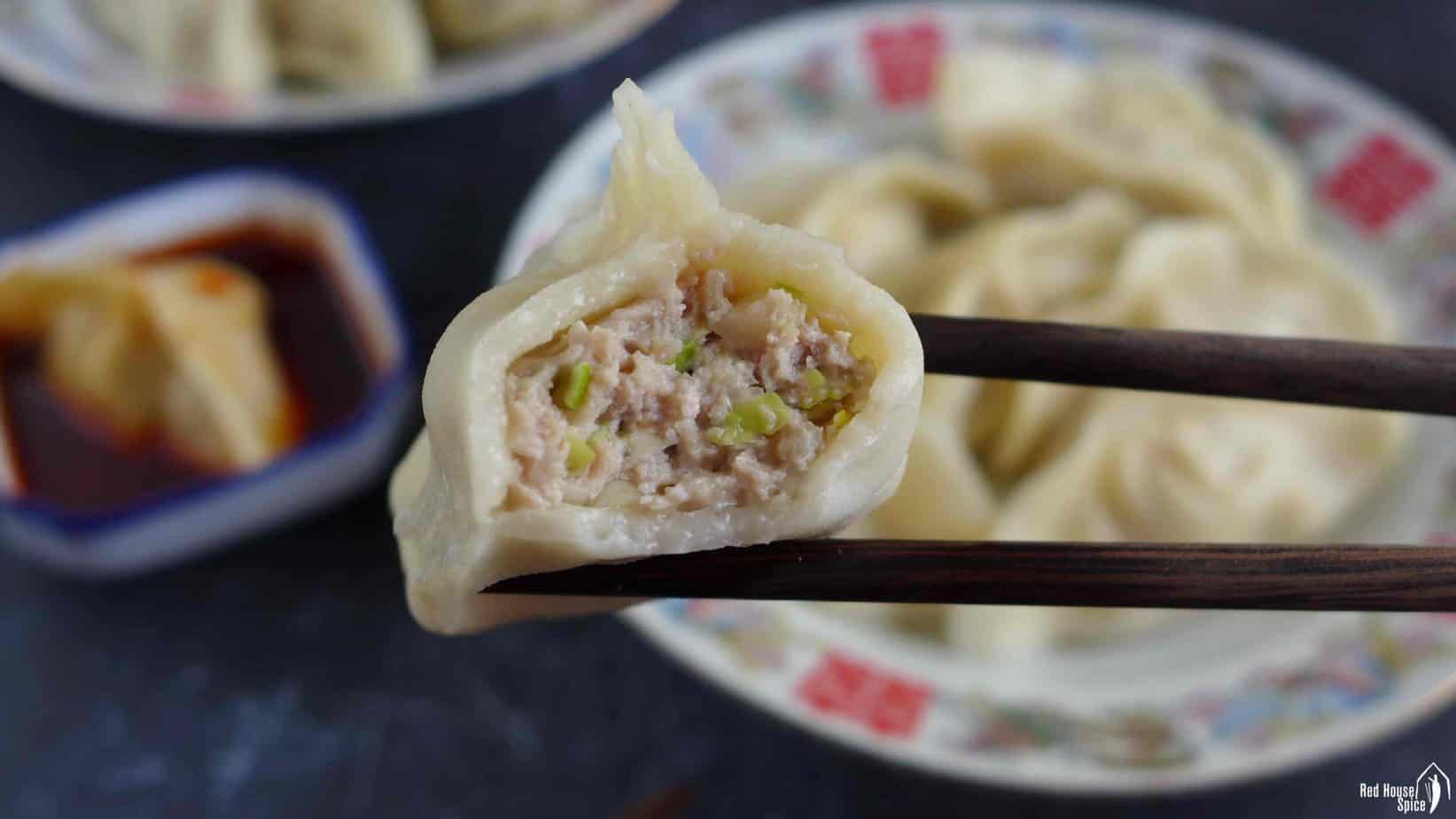 a half eaten dumpling picked up by chopsticks