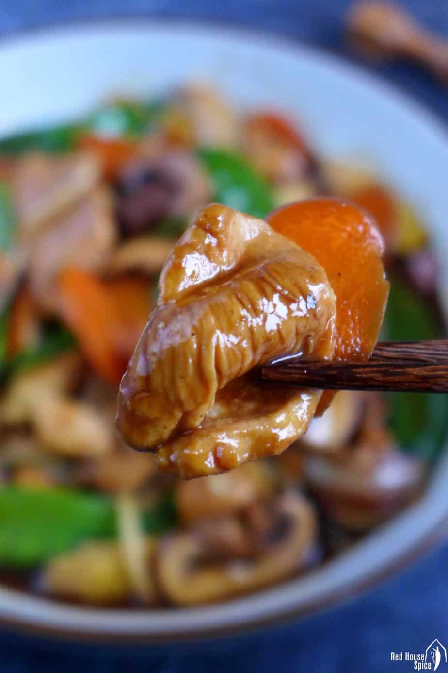 A piece of chicken held by chopsticks