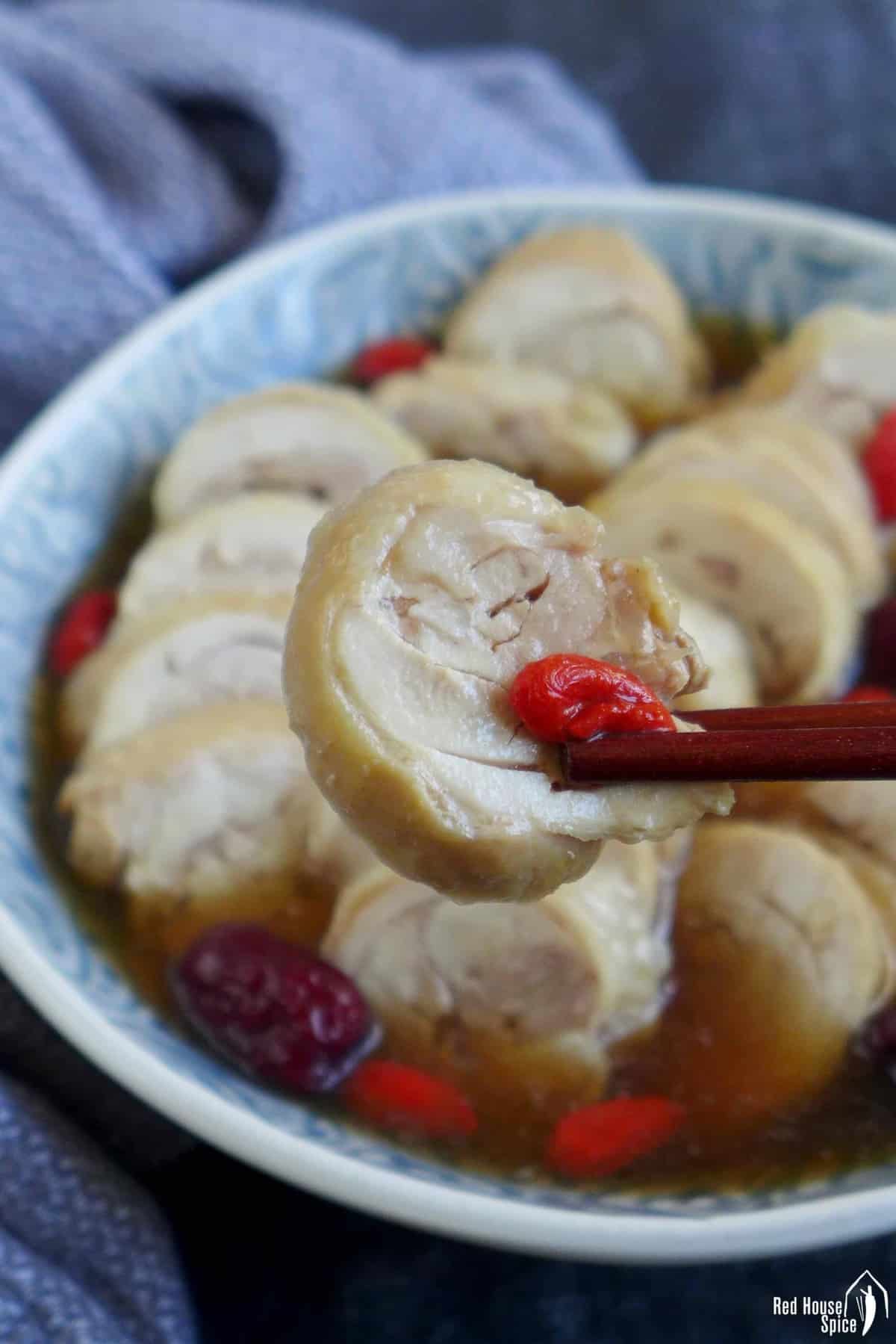 a piece of drunken chicken held by chopsticks
