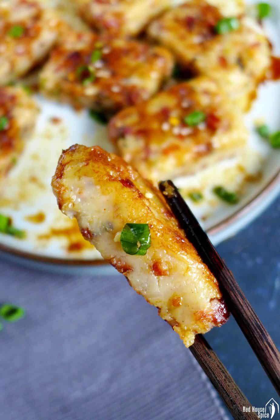 A piece of turnip cake held by chopsticks