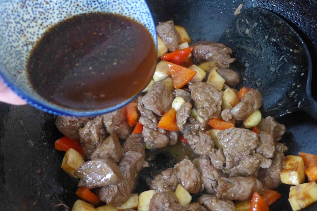 pouring sauce over beef and vegetables.