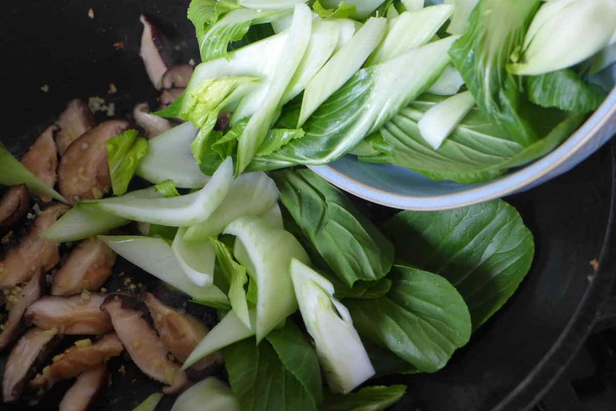 adding bok choy to the wok.