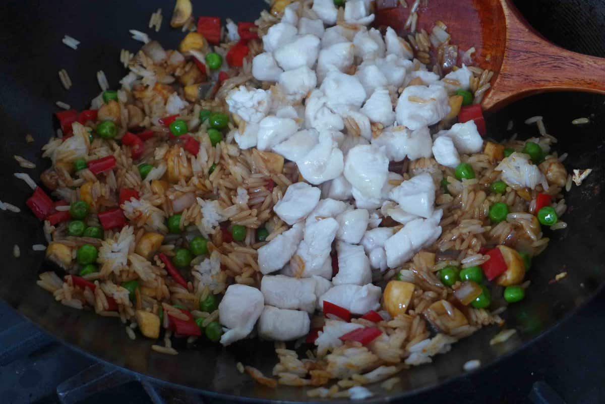 adding cooked chicken over rice and vegetables.