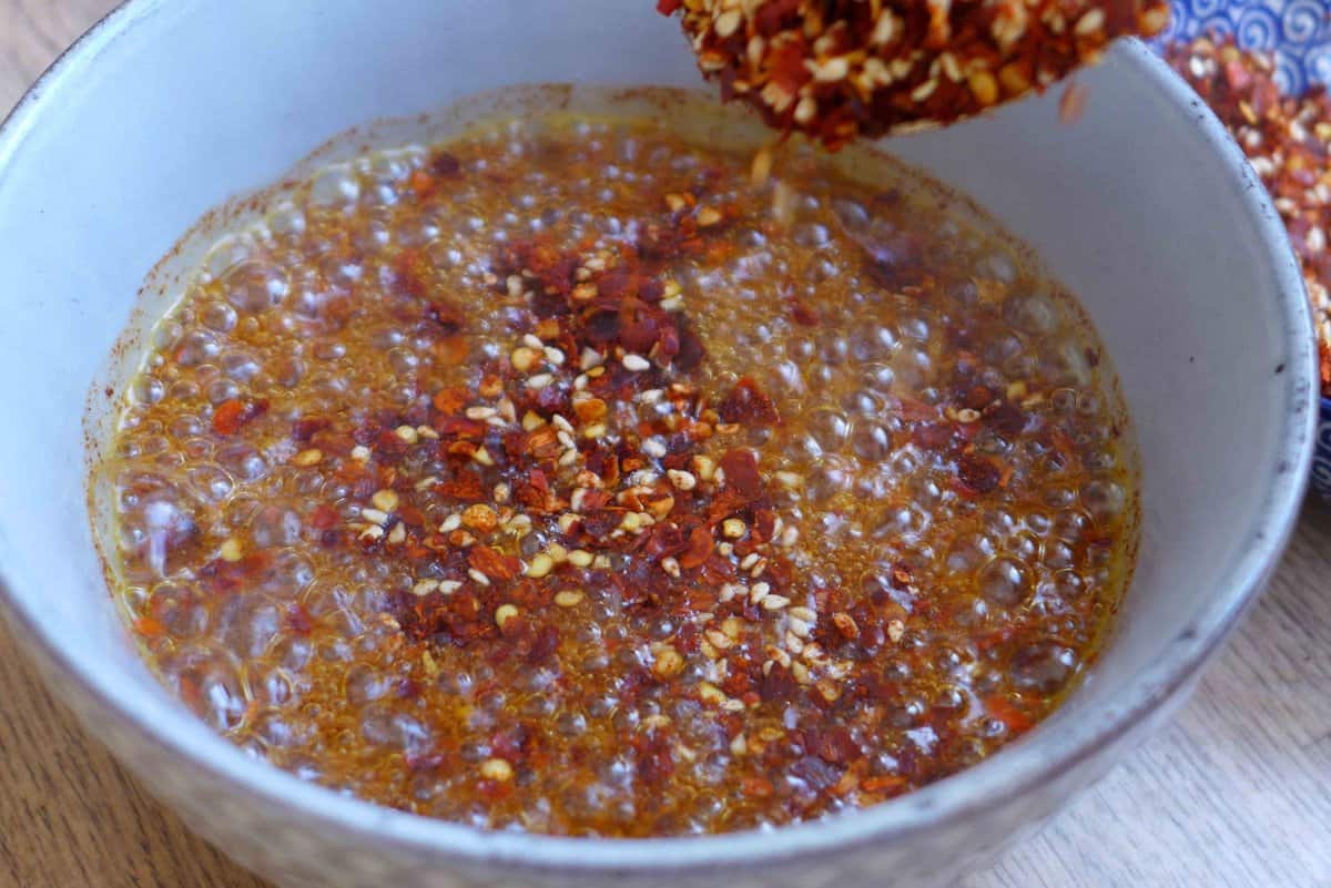 Adding chili flakes to hot oil.