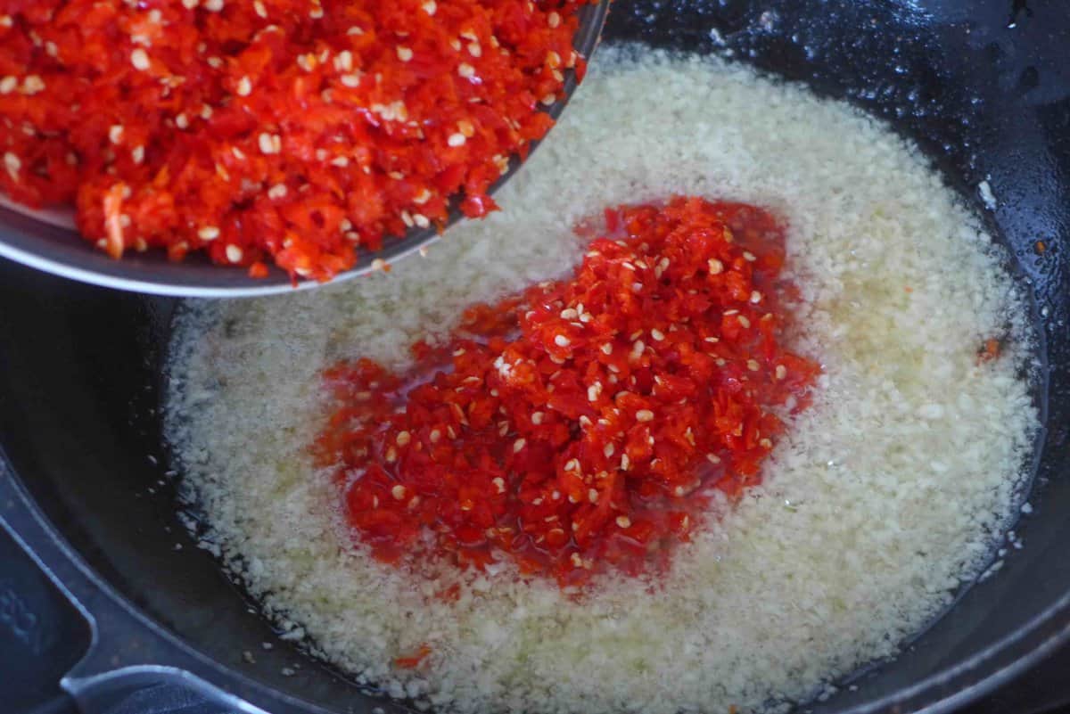 adding minced garlic and fresh chili to oil.
