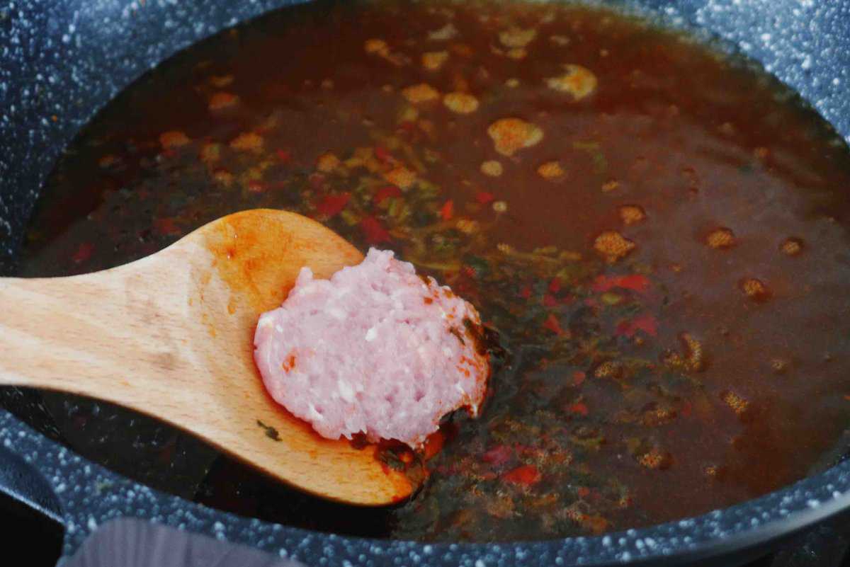putting a meat patty into soup.