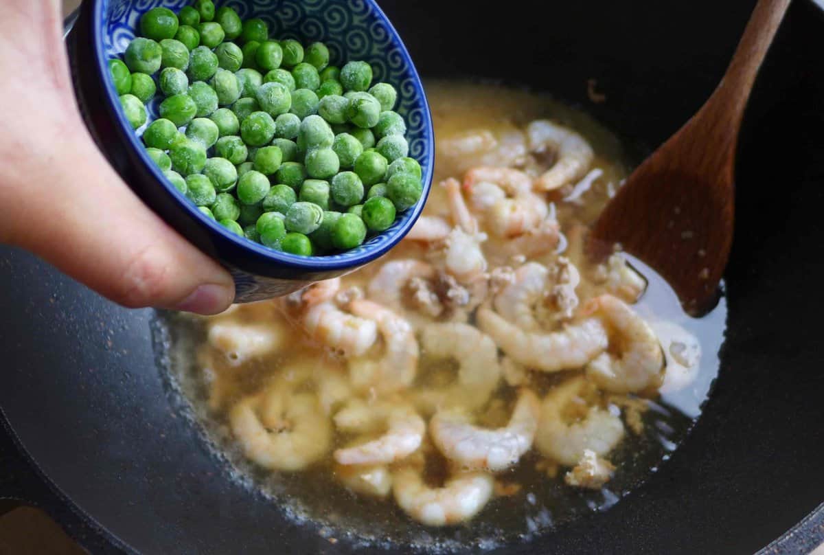 adding peas to shrimp and broth.