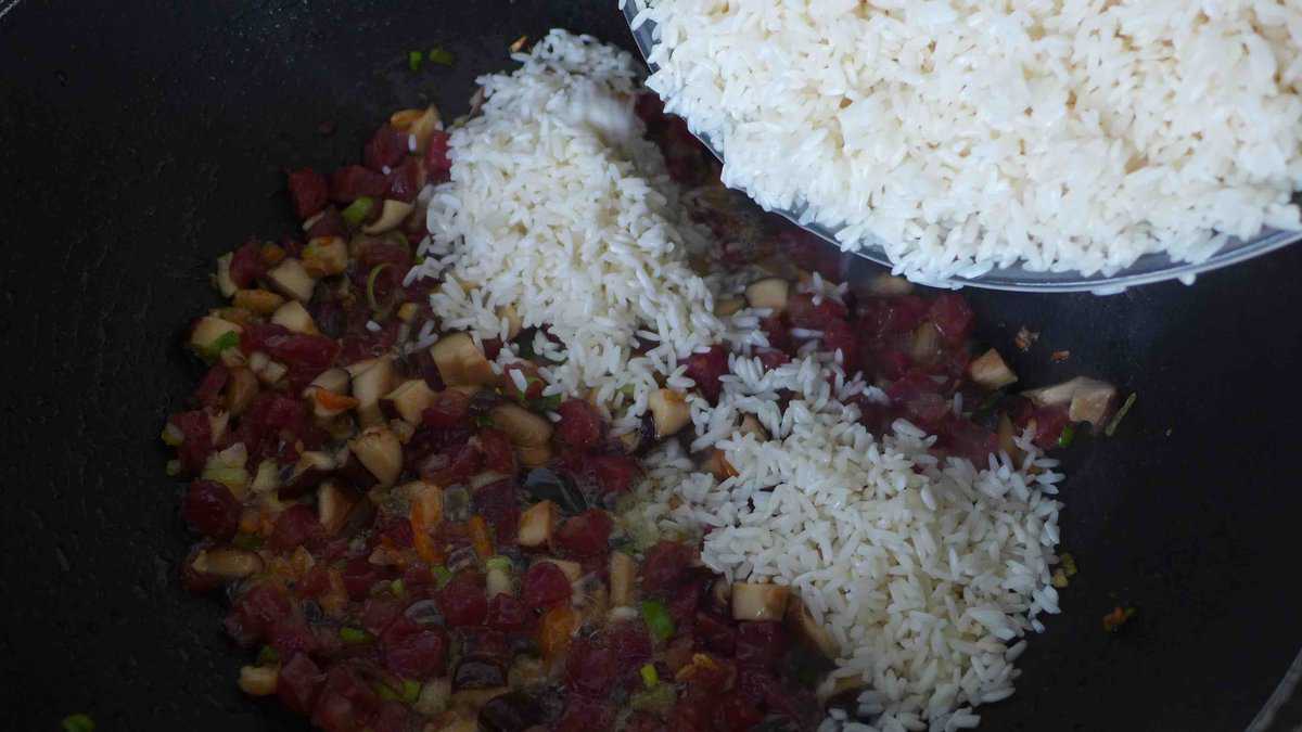 adding drained glutinous rice to a wok.