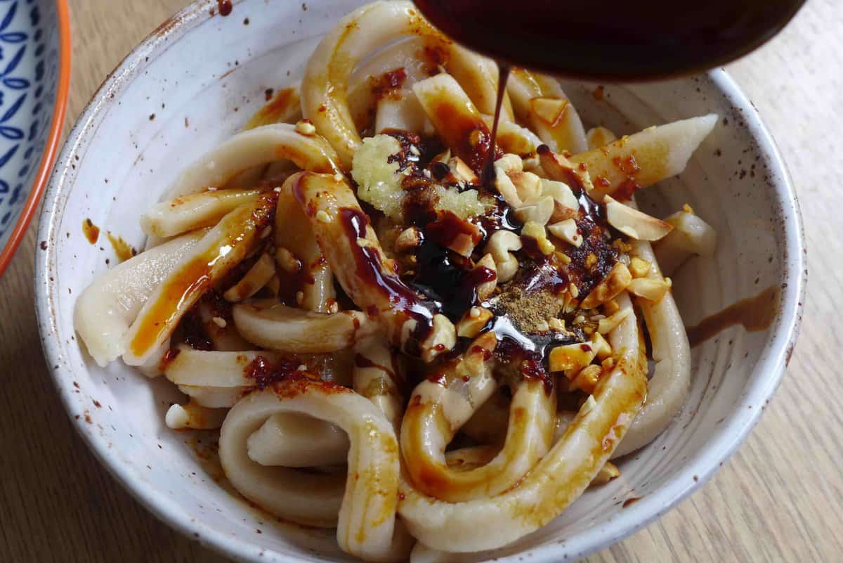 adding sauce to noodles.