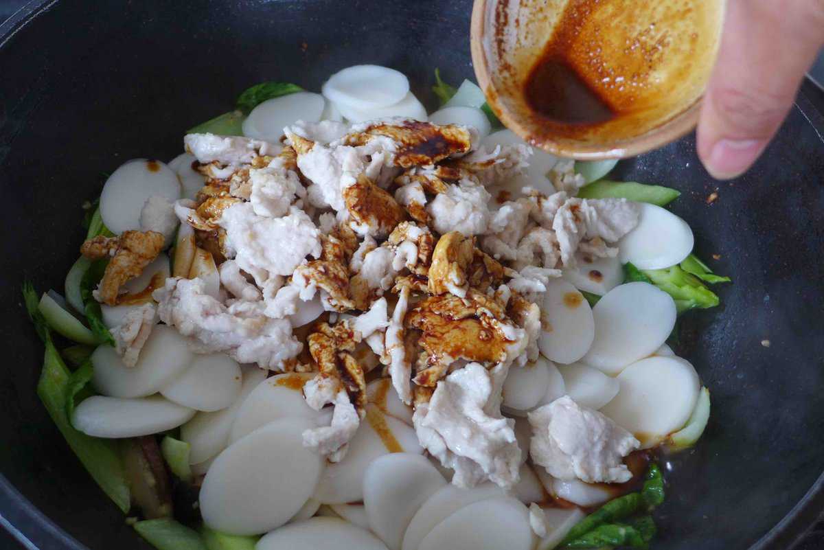 adding sauce to rice cake stir-fry.