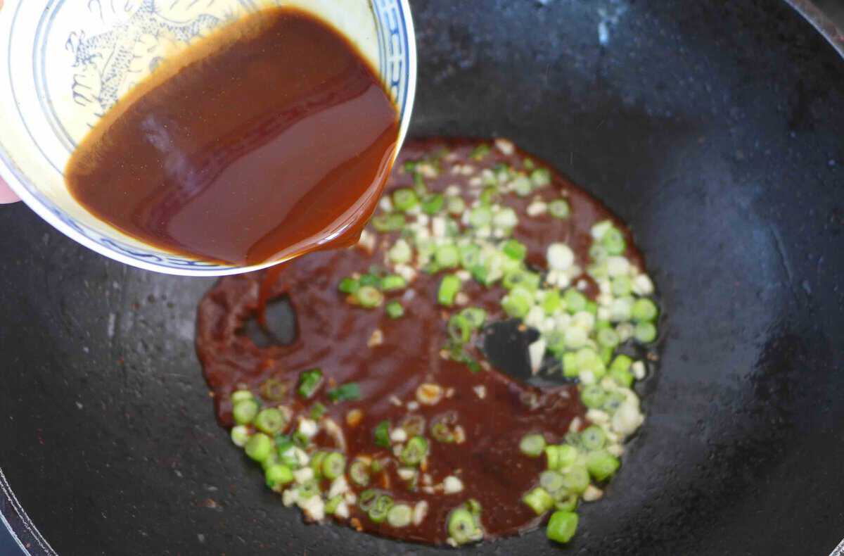 pouring sauce into a wok.