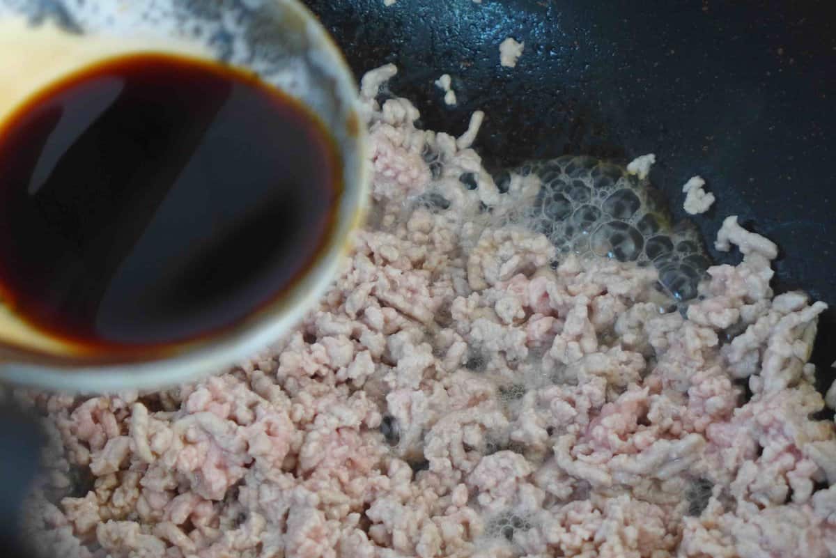 adding soy sauce to fried ground pork.