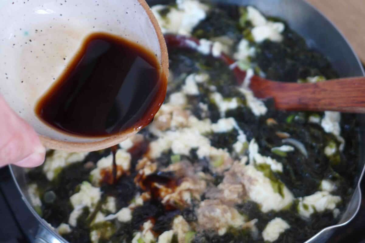 pouring soy sauce and rice vinegar to soup.