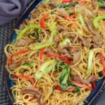 a plate of beef chow mein with sha cha sauce.