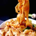 wide noodles picked up by chopsticks.