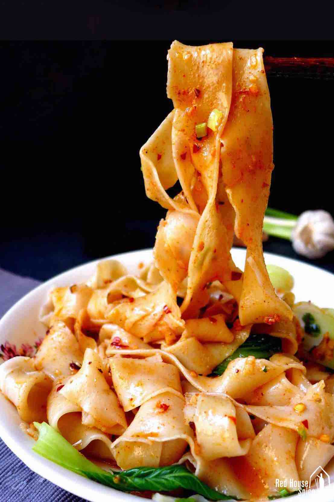 wide noodles picked up by chopsticks.