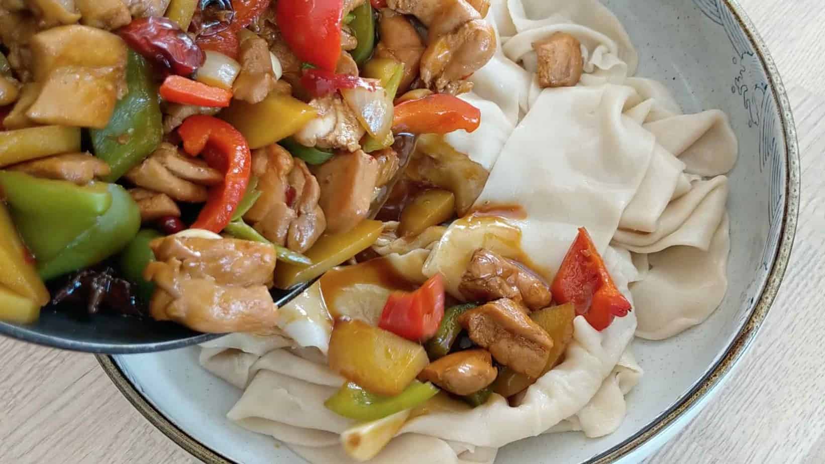 Pouring chicken stew onto noodles