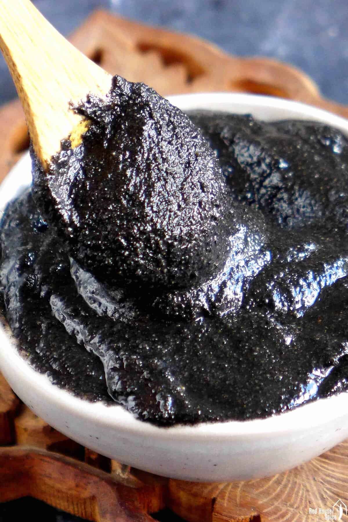 Scooping black sesame paste with a spoon.