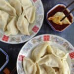 two plates of pork dumplings and a dipping sauce