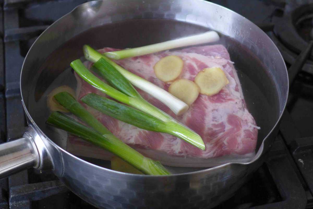 cooking pork belly in water with scallions and ginger.
