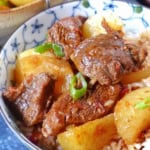 braised beef with daikon over steamed rice with overlay text that says braised beef & daikon.