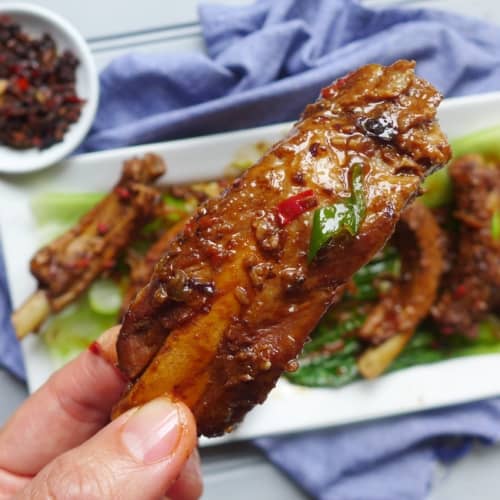 a braised pork rib held by a hand