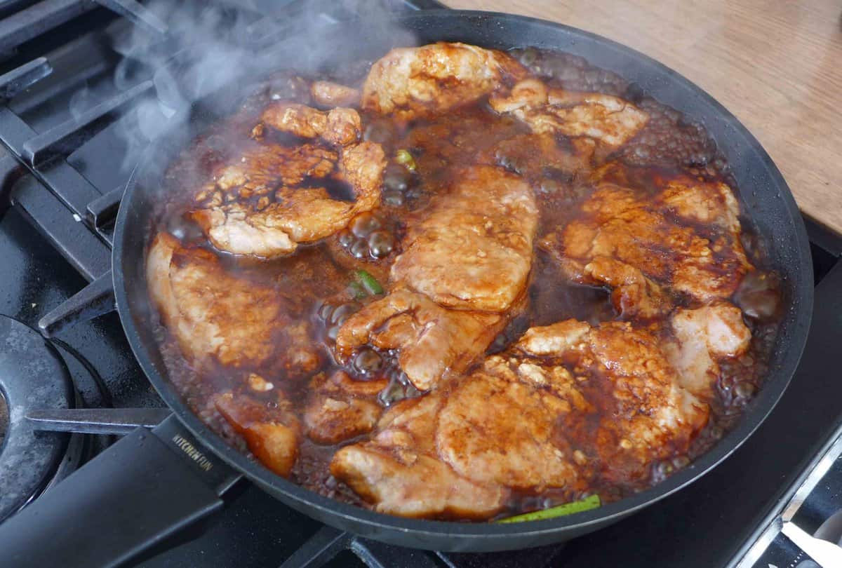 braising pork chop and scallions in sauce.