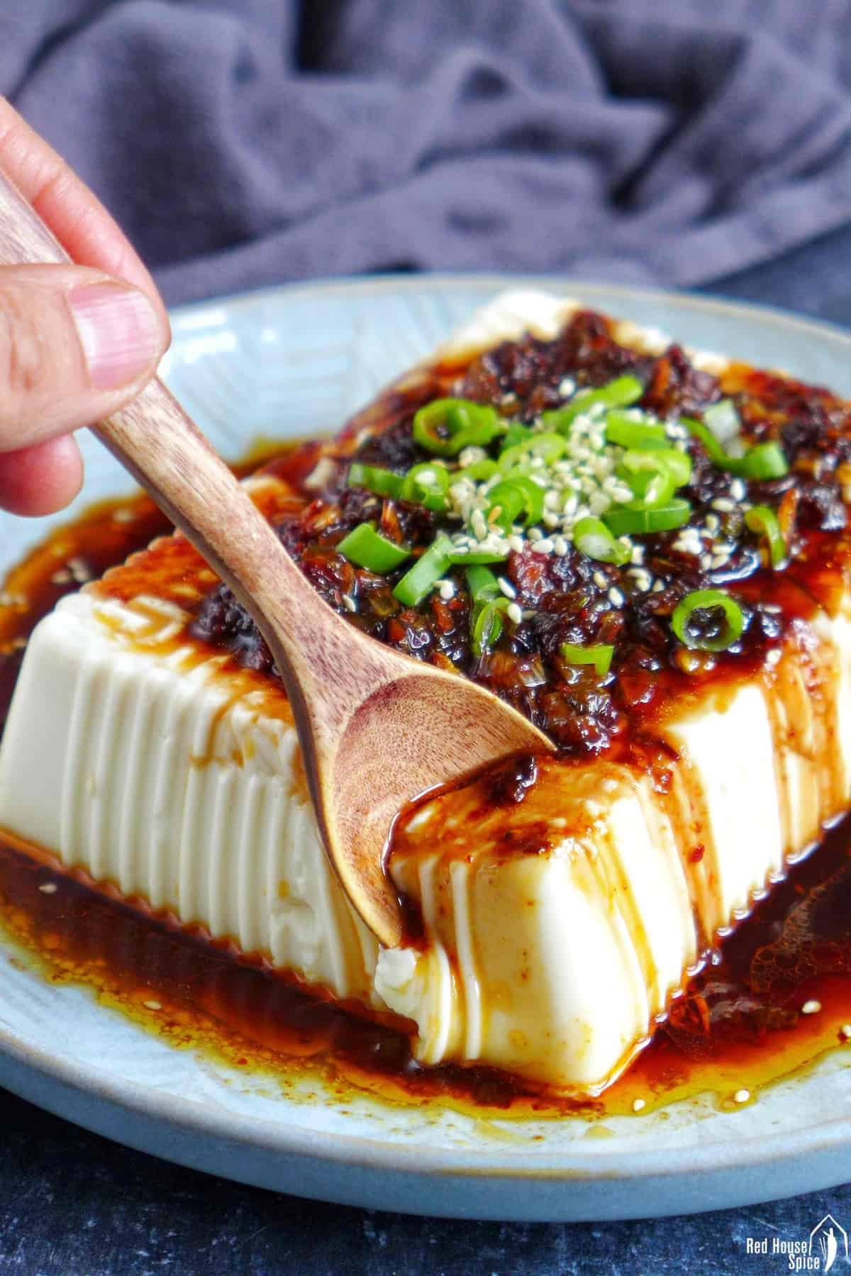 a spoon breaking a piece of silken tofu