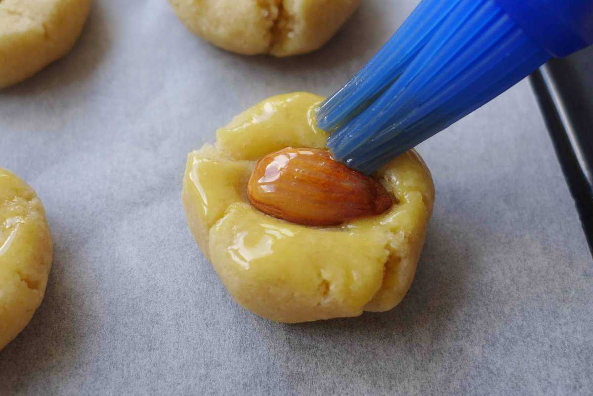 brushing egg yolk over uncooked cookies.