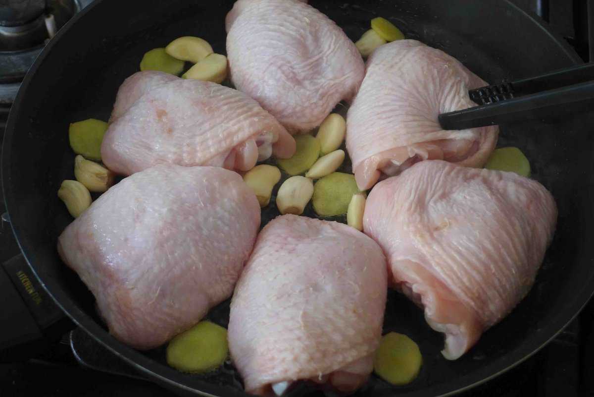 raw chicken thighs, ginger and garlic in a skillet.