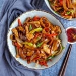 a bowl of chicken chow fun with chili oil on the side.