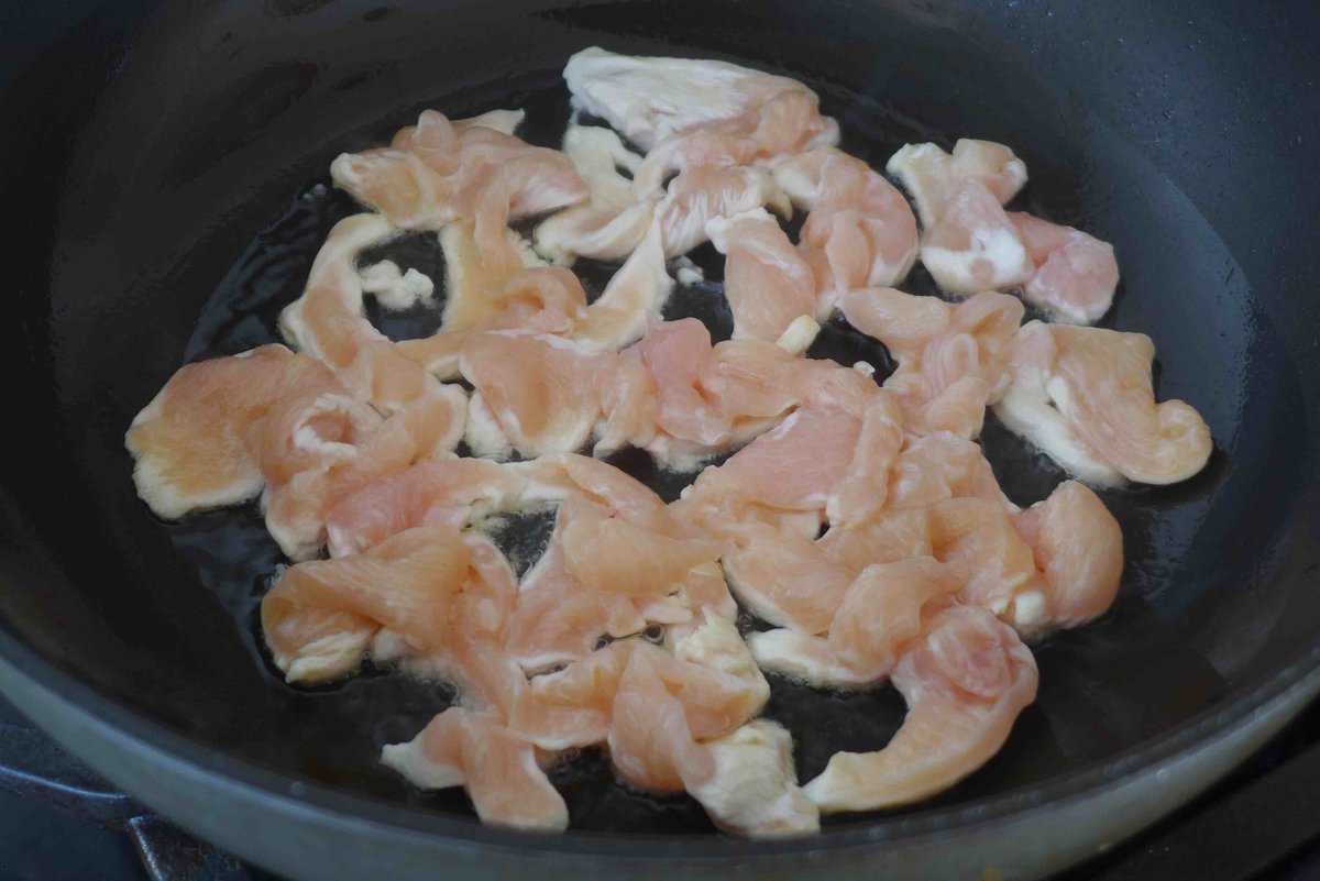 raw chicken pieces sizzling in oil.
