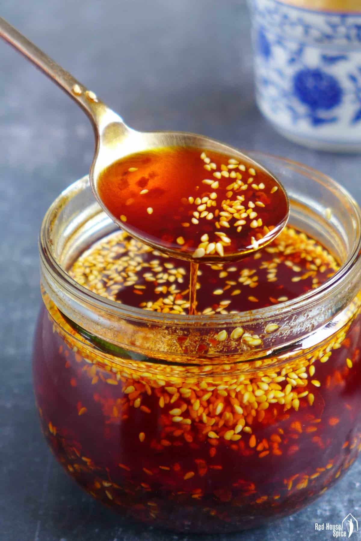 Chili oil in a spoon over a jar.
