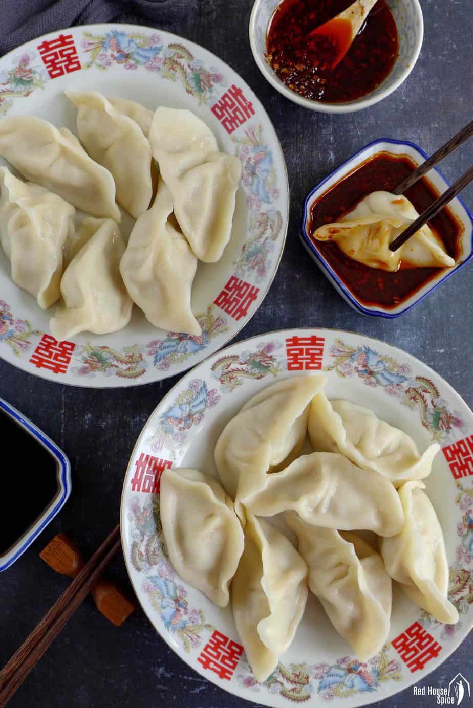 Two plates of pork dumplings and a dipping sauce