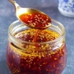 Chili oil in a spoon over a jar.