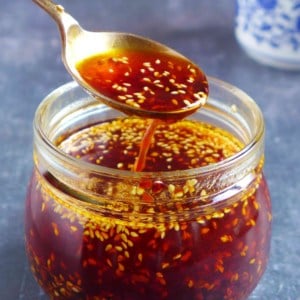 Chili oil in a spoon over a jar.