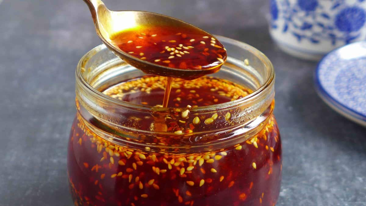 Chili oil in a spoon over a jar.