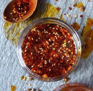 A jar of freshly made Chinese chilli oil with a spoon on the side.