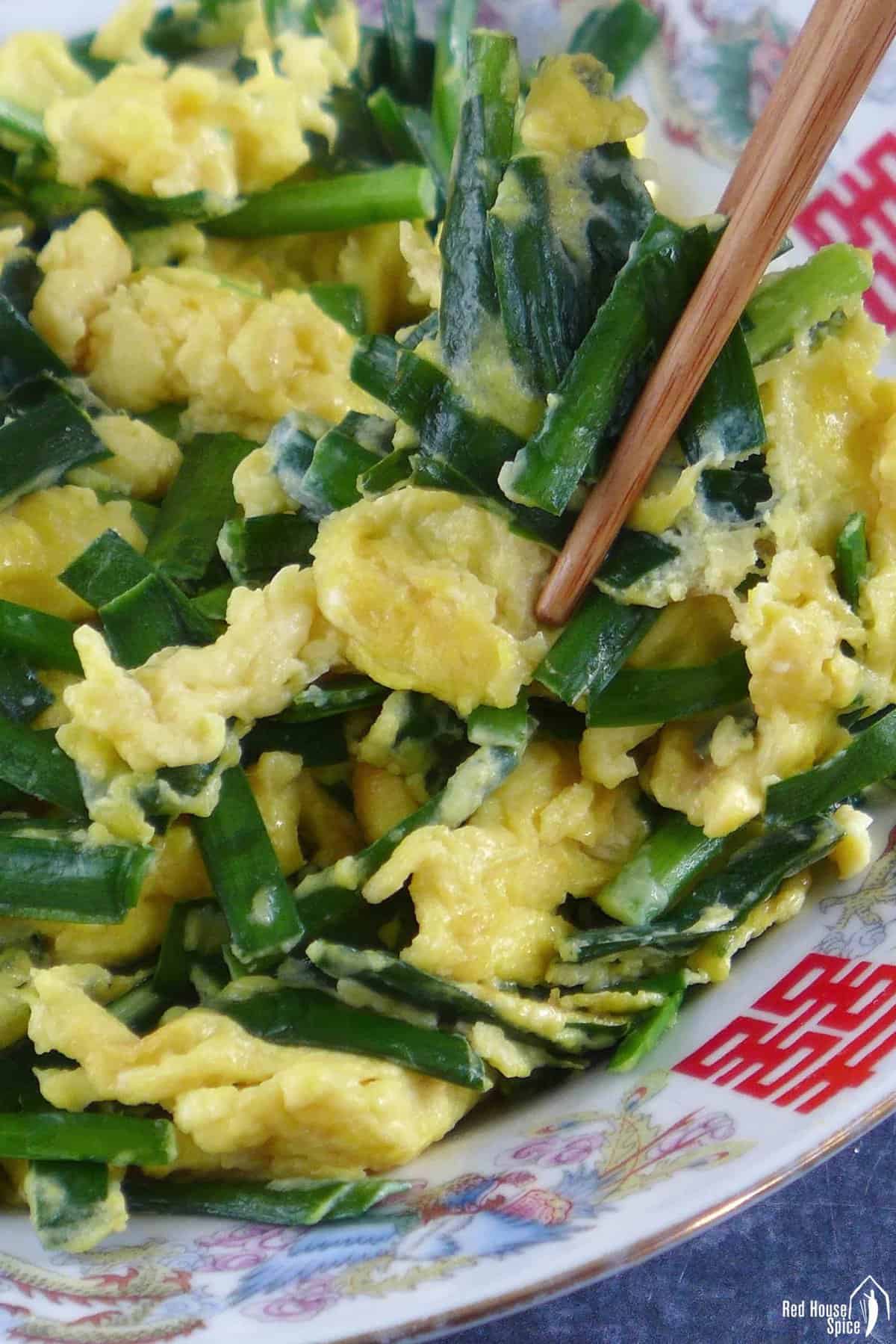 chopsticks picking up stir-fried chinese chive and egg.