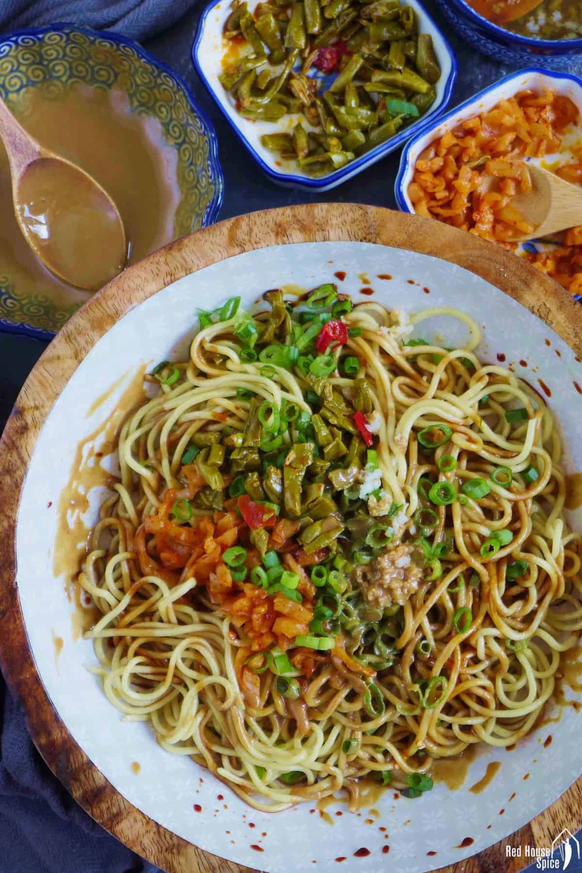 A bowl of hot dry noodles with toppings on the side
