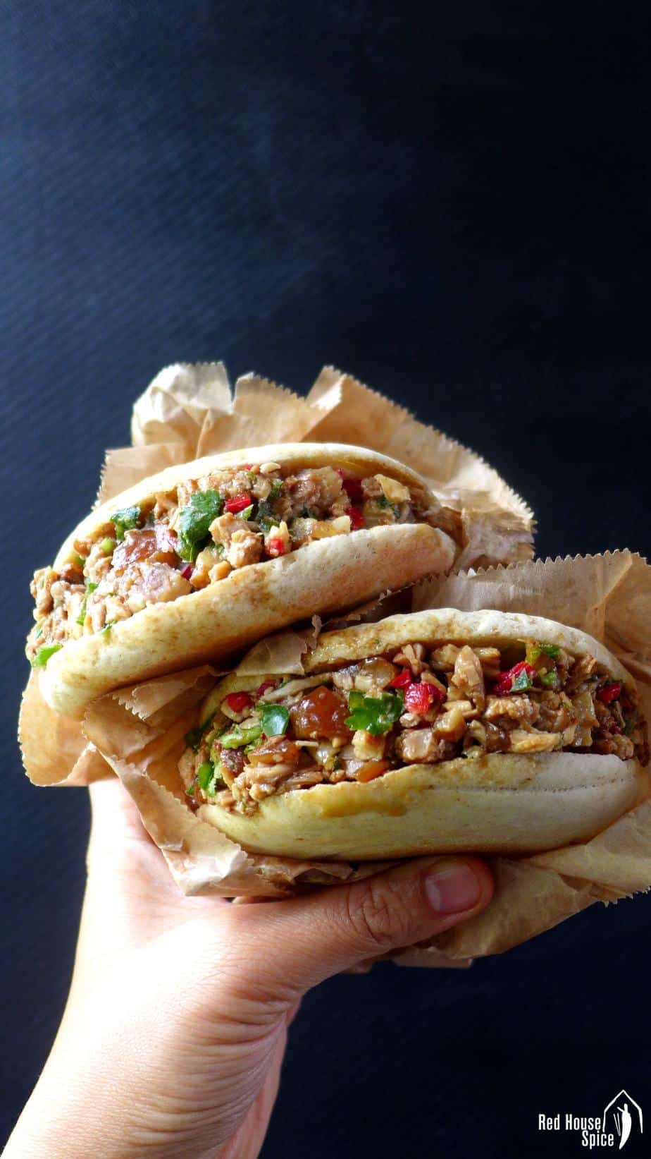 Two Chinese pork burgers held by a hand.