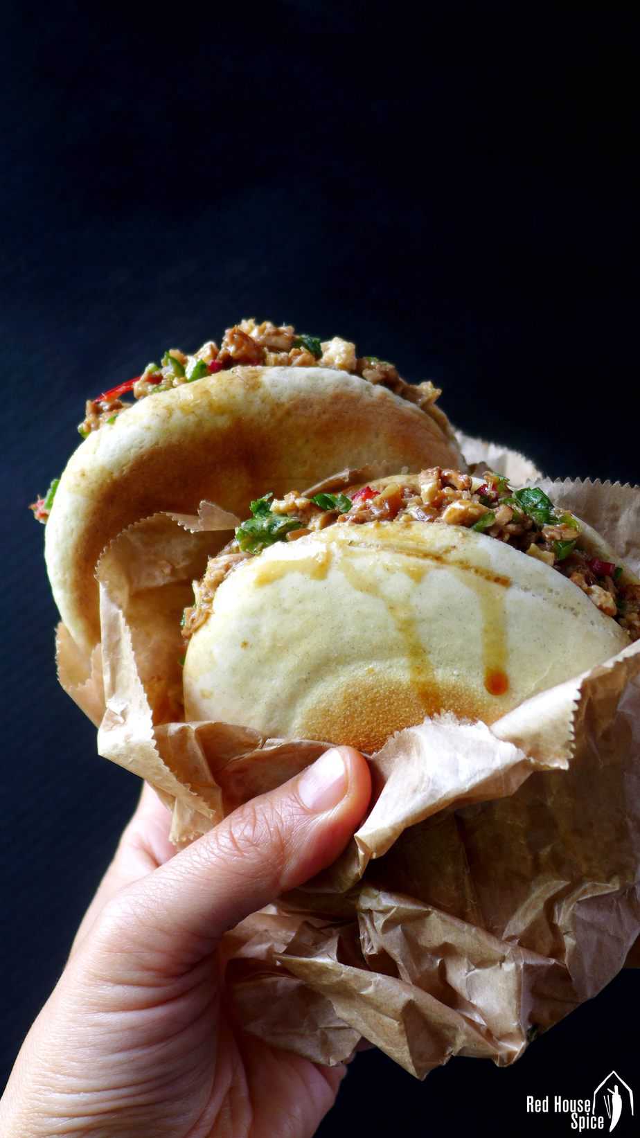 Two Chinese pork burgers held by a hand.