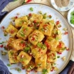 A plate of Chinese salt and pepper tofu with salt and pepper seasoning on the side