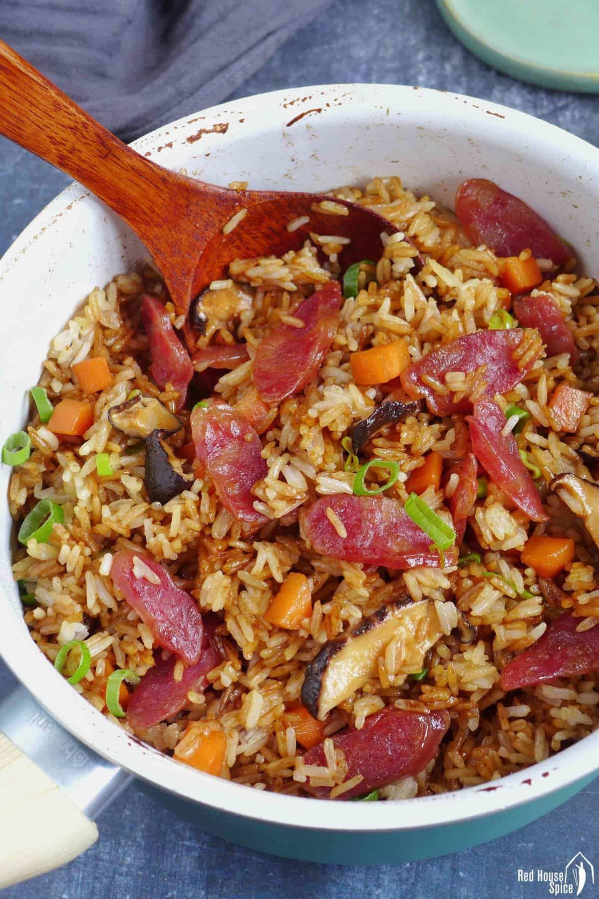 Chinese sausage rice with carrots and mushroom in a saucepan.