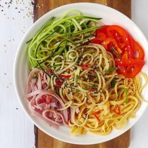 A bowl of spaghetti noodles with ham, eggs, courgette & pepper.
