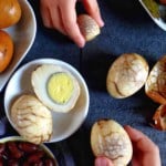 two hands holding a tea marinated hen egg and a tea marinated quail egg.