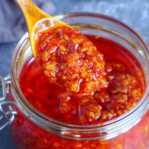 scooping out chiu chow chili oil from a jar.