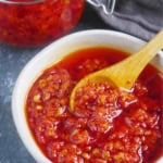 chili oil in a bowl and in jars with overlay text that says chiu chow chili oil.