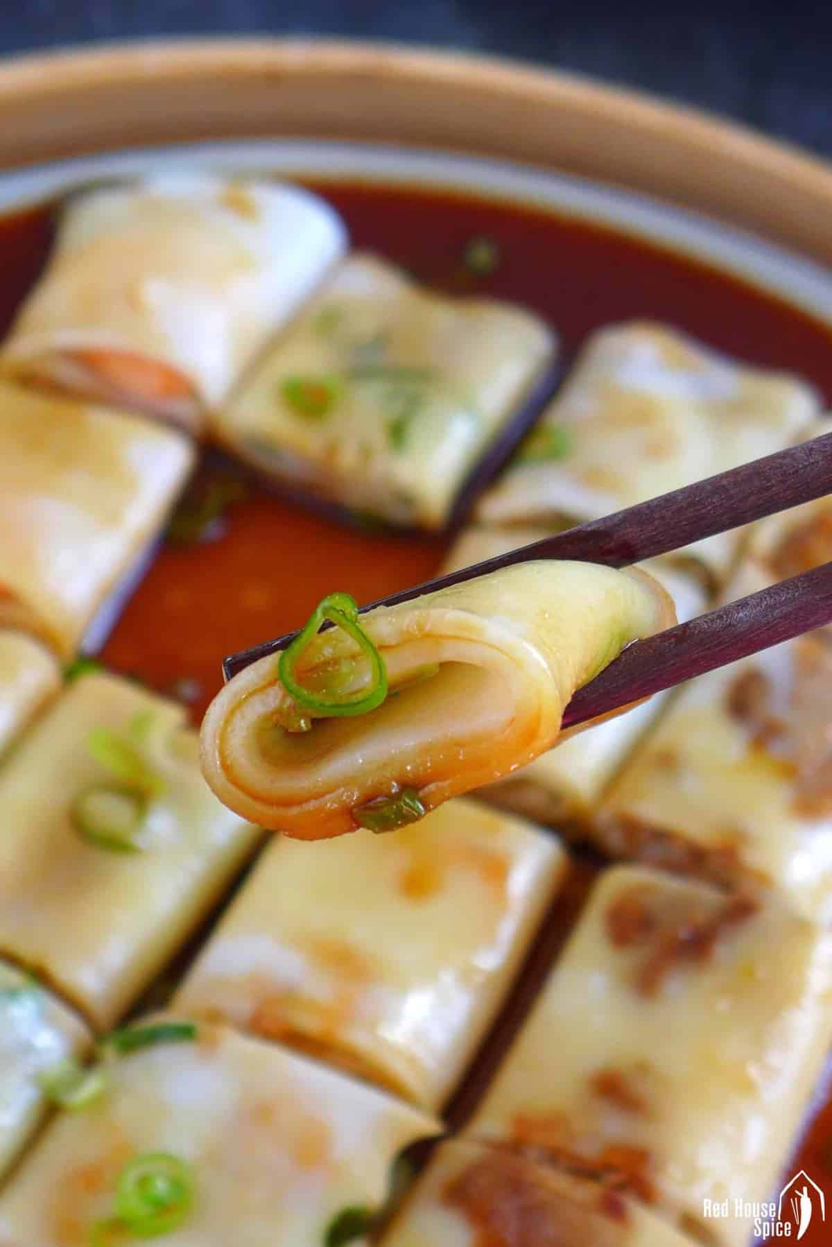 a piece of Cheung fun held by chopsticks