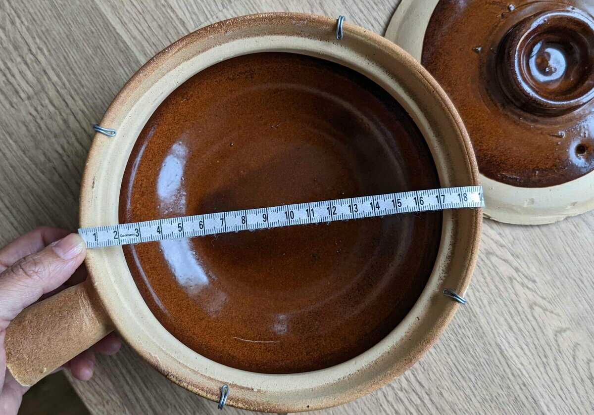 An empty chinese clay pot with a measuring tape.